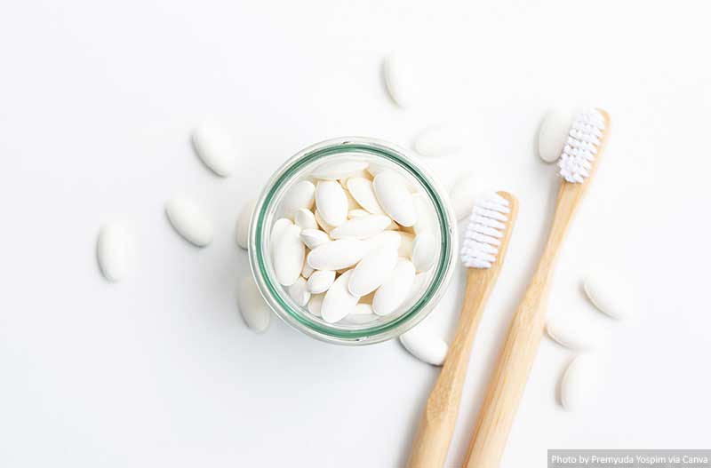Toothpaste tablets in a glass bottle with bamboo toothbrushes